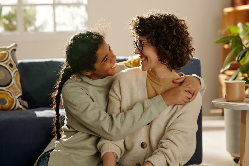 Smiling child hugging adult on living room floor